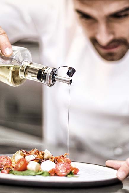 Chef drizzles olive oil atop salad at Gourmet Dining and eclectic cuisine & lounge at Chefusion Restaurant and bar in Green Bay, Wisconsin