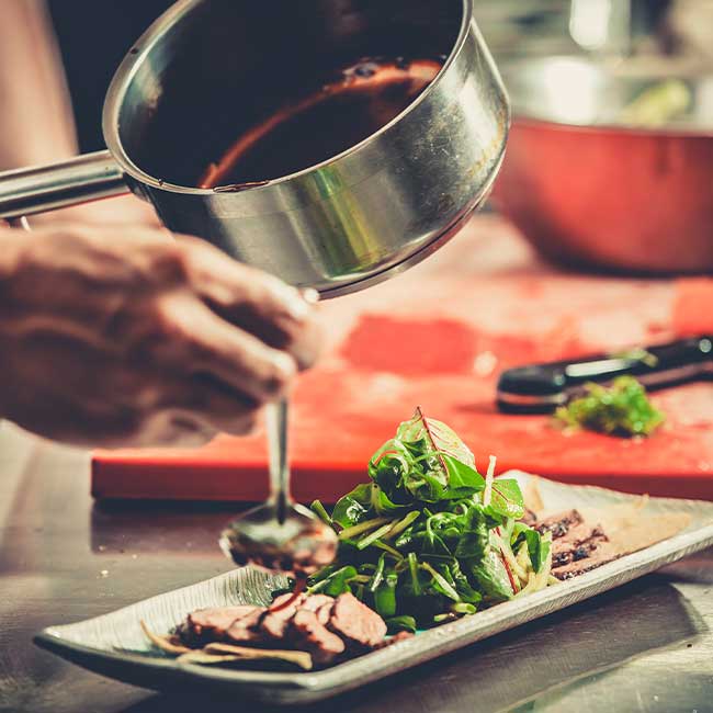 Gourmet chef drizzles red wine reduction atop salad at eclectic cuisine & lounge: Chefusion Restaurant and bar in Green Bay, Wisconsin